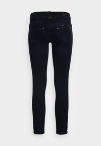 Mörkblå smala jeans i denim, med fem fickor, diskret sömnad och knappdetaljer vid ankelsömmen.