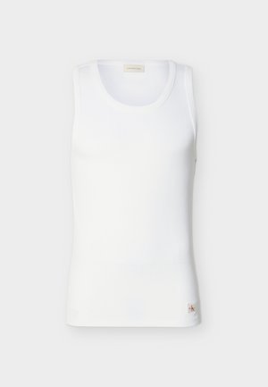 Valkoinen ribbineulottu hihaton toppi pyöreällä pääntiellä ja pienellä Calvin Klein -logotunnisteella helman läheisyydessä, yksivärisellä taustalla.
