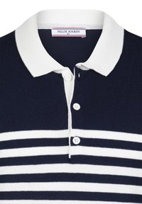 Marinblå og hvid stribet polo t-shirt lavet af strikket stof, med en hvid krave og tre hvide knapper ved halsen. Mærkeetiket synlig.