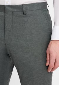 Grey tailored trousers made from a textured fabric, featuring a slim fit, side pockets, and a flat front design.