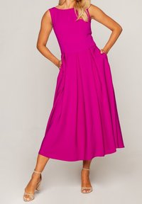 Robe sans manches fuchsia avec un col rond, un corsage ajusté et une jupe évasée avec des poches, en tissu lisse.