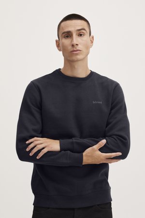Dark navy sweatshirt with a round neck, ribbed cuffs, and a small logo on the chest. Soft fabric with a smooth texture, relaxed fit.