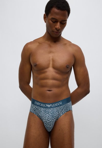 Pánské slipy v tmavě modré barvě s bílým texturovaným vzorem. Elastický pas s nápisem "Emporio Armani". Hladký, přiléhavý střih.