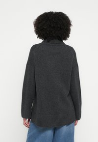 Pulover tricotat gri cărbune cu guler înalt, mâneci raglan și tiv cu dungi. Partea din spate are un design simplu, fără cusături.