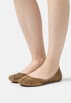 Bailarinas marrones hechas de material trenzado. Punta redondeada con una forma flexible. El diseño presenta una superficie texturizada con patrones intrincados.