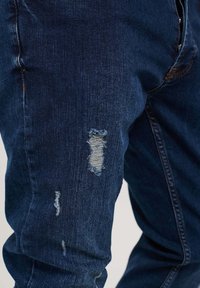 Pieguloša piegriezuma džinsi - blue