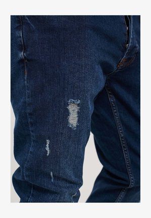 Denim jeans in dark blue with distressed areas featuring frayed edges. Standard fit with visible stitching and a smooth texture.