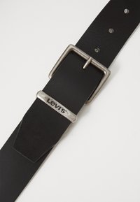 Melnas ādas josta ar sudraba taisnstūra sprādzi, kurai ir Levi's logo. Josta ir gluda, ar caurumiem izmēra pielāgošanai.