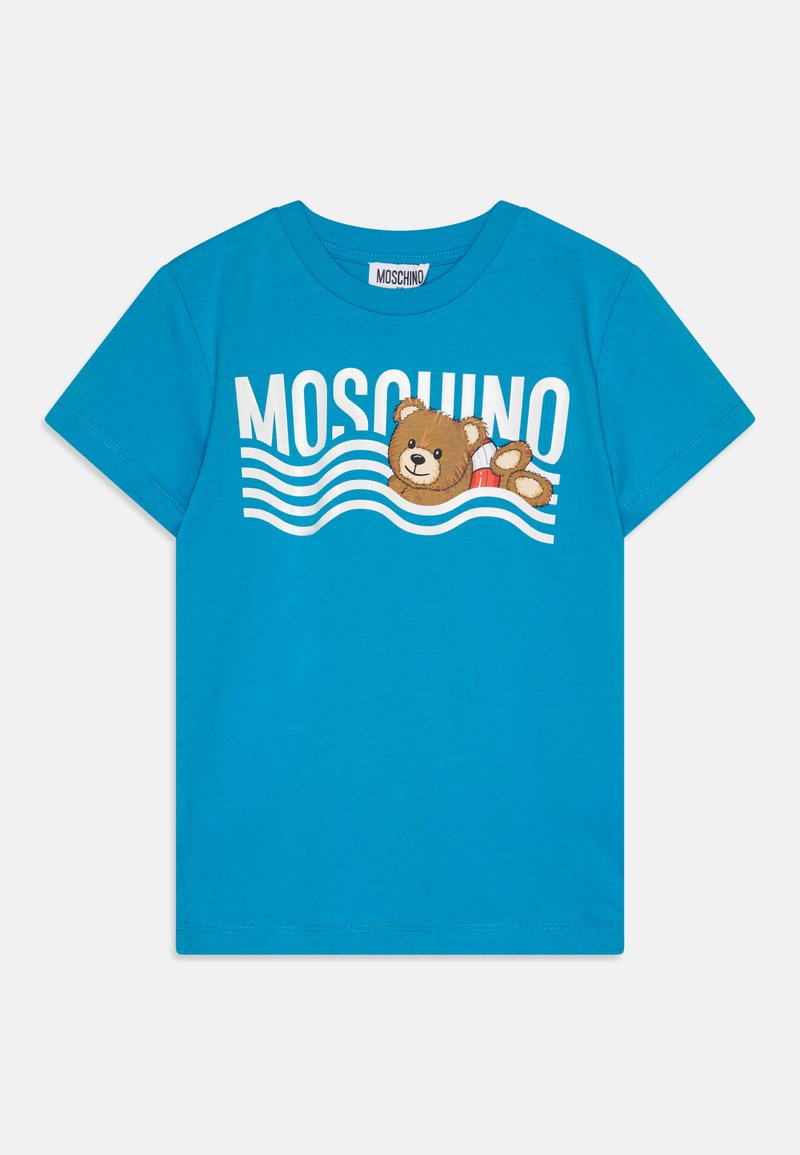Τυρκουάζ βαμβακερό μπλουζάκι με σχέδιο ενός καρτούν αρκούδας και κυμάτων, με το "MOSCHINO" τυπωμένο σε έντονη λευκή γραφή πάνω από το σχέδιο.