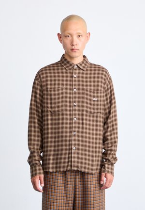 Brown and beige checked shirt with long sleeves, two chest pockets, and buttons. Features an embroidered logo on the left pocket.