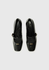 Black patent leather Mary Jane shoes with a square toe, buckle strap, and gold logo detail on the side. Smooth and glossy texture.