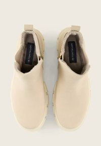 Beige instappers met enkelhoge laarzen met een gladde oppervlakte, rubberen zool en zijritsen. Het interieur heeft een zachte voering en een logo-label.