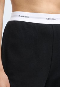Melna ribota josta ar "Calvin Klein" logo baltā krāsā. Materiāls ir mīksts un elastīgs, nodrošinot komfortu un izturību.