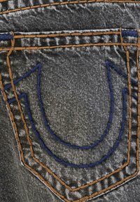 Gray denim jeans featuring prominent blue and orange stitching in a U-shaped design on the back pocket. Smooth texture with subtle sheen.