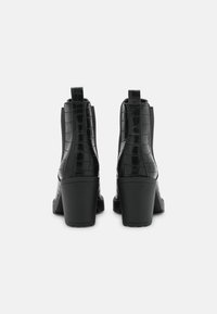 Botas de tobillo negras con tacón, con un patrón de cocodrilo brillante, paneles laterales elásticos y lengüetas en la parte posterior. Diseño de tacón robusto.