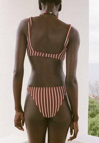 Bikini komplet v maroon in beli črtasti dizajn, ki vsebuje top s kvadratnim izrezom in nizkimi hlačkami, izdelan iz teksturirane tkanine s tesnim prileganjem.