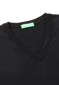 Černý pletený svetr s výstřihem do V a žebrovaným límečkem. Na štítku je zelený nápis "UNITED COLORS OF BENETTON." Hladká textura.