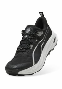 Czarne buty sportowe z teksturowaną cholewką, białą podeszwą środkową i wzorzystą czarną gumową podeszwą. Posiadają odblaskowe akcenty i mocne sznurówki.