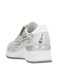 Baskets blanches avec un talon argenté texturé, des accents brillants et un design imprimé avec divers mots liés à la chaussure en noir.