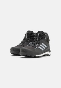 Botas de senderismo negras con acentos blancos, parte superior de malla texturizada, suela de goma duradera, puntera reforzada y un sistema de cordones destacado.