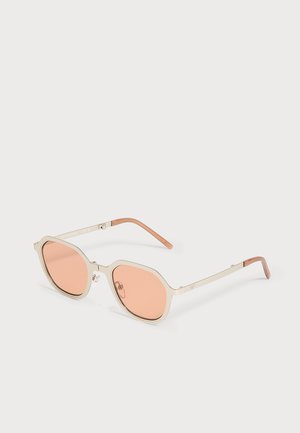 Metallgerahmte Sonnenbrille mit pfirsichfarbenen, runden Gläsern und dünnen Bügeln mit braunen Spitzen auf weißem Hintergrund.