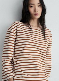 T-shirt à manches longues rayé en crème et rouille, avec un grand col et un tissu doux et lisse offrant une coupe décontractée.