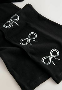 Črn material s tremi pentljami okrašenimi z rhinestones, ki prikazuje gladko teksturo in klasičen dizajn. Akcenti so sijoči in dekorativni.