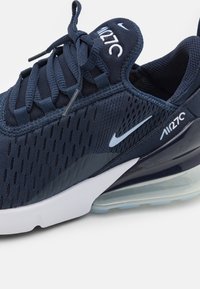 Mörkblå Nike Air Max 270-sneaker med ovandel i mesh med perforeringar, en vit mellansula och en synlig luftkuddenhet.