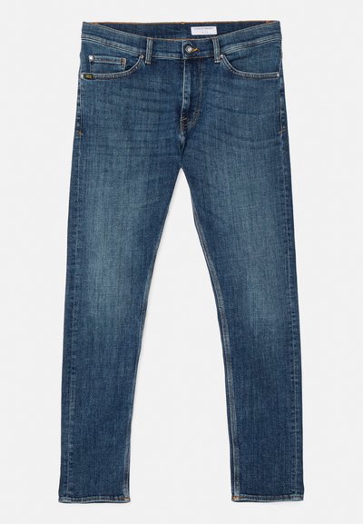 Jeans de mezclilla azul oscuro con corte slim, diseño clásico de cinco bolsillos, costuras visibles y una cintura ajustada. Sin adornos ni estampados.