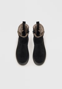 Zwarte suede enkellaarzen met een zachte, beige nep-bont voering. Voorzien van zijritsen en een getextureerde rubberen zool. Gladde bovenkant.