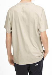 Beige bavlněné tričko s volným střihem, kulatým výstřihem a krátkými rukávy. Obsahuje šev na zadní straně.