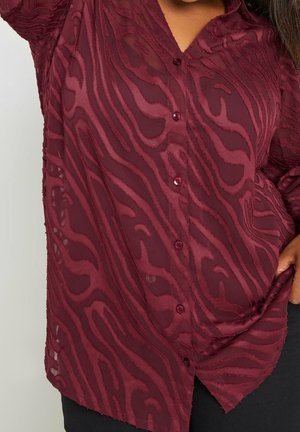 Bordeauxrote Hemdbluse mit strukturiertem, wellenförmigem Muster, aus transparentem Stoff mit passenden Knöpfen, entworfen für eine lockere Passform.