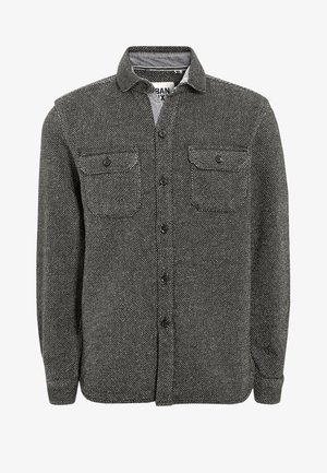 Chemise à manches longues boutonnée en tissu texturé noir et blanc avec deux poches poitrine boutonnées et un col.