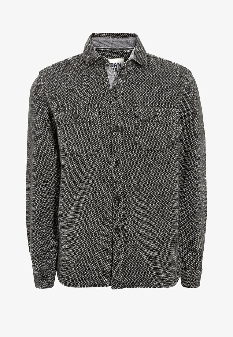 Chemise à manches longues boutonnée en tissu texturé noir et blanc avec deux poches poitrine boutonnées et un col.