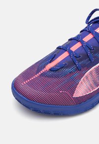 Scarpa sportiva con una parte superiore in mesh multicolore, nei toni del viola e del rosa, caratterizzata da una trama testurizzata. Presenta lacci a contrasto e una suola in gomma con trazione.