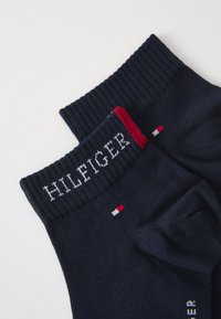 Navyfarbene Socken aus Baumwolle mit gerippter Textur am Bündchen, „HILFIGER“-Logo in Weiß und kleinen roten und weißen Akzenten.