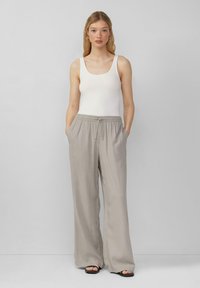 Lichtgrijze wijde broek met elastische tailleband en trekkoord, gecombineerd met een aansluitend wit tanktop. Gladde textuur met zijzakken.