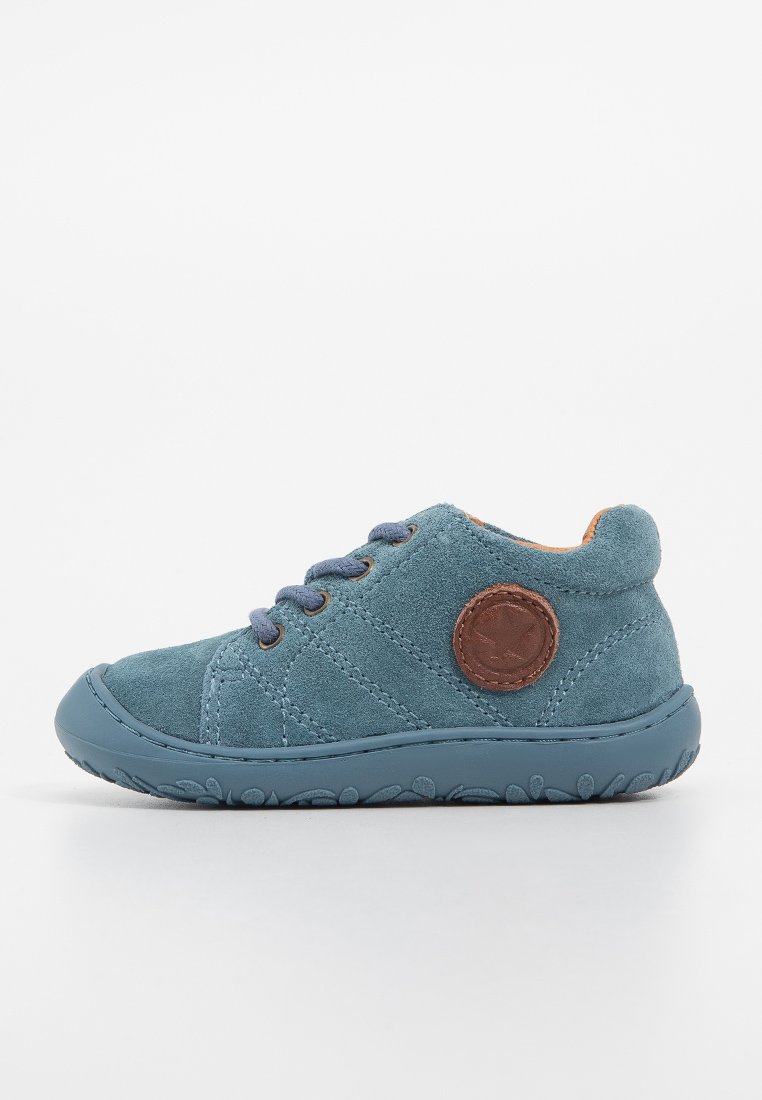 Blaue Wildleder-Schuhe mit einer Schnürung, runder Zehenform und einem braunen Logo-Patch. Texturierte Oberfläche und flexible Gummisohle mit floralem Muster.