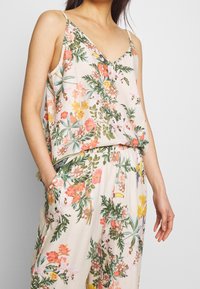 Top senza maniche con stampa floreale e scollatura a V, caratterizzato da tonalità di rosa, giallo e verde, realizzato in un tessuto leggero e testurizzato.