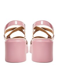 Sandali in pelle verniciata rosa con design a fibbia incrociata e tacchi a piattaforma solidi e spessi di colore rosa. L'interno presenta una fodera beige.