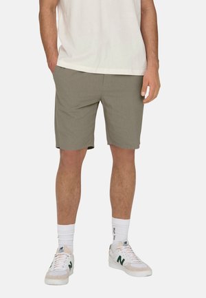 Pantaloni scurți gri deschis cu o croială lejeră, confecționați dintr-un material moale. Purtați cu adidași albi și șosete albe texturate pentru un aspect casual.