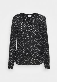 Schwarze Bluse mit langen Ärmeln und V-Ausschnitt, versehen mit einem weißen Punktemuster und einem strukturierten Stoff. Der Saum ist am Boden leicht gekrümmt.