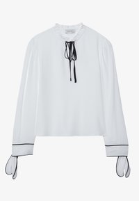Biała bluzka z długim rękawem, z falbanką przy dekolcie, ozdobnymi czarnymi wiązaniami i kontrastującym czarnym wykończeniem na mankietach. Gładka faktura materiału.