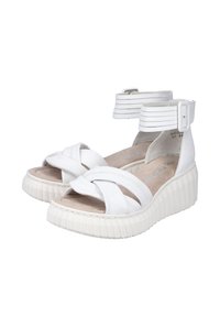 Sandales blanches avec des brides croisées et une bande de cheville, présentant une semelle en plateforme texturée et un revêtement intérieur lisse.