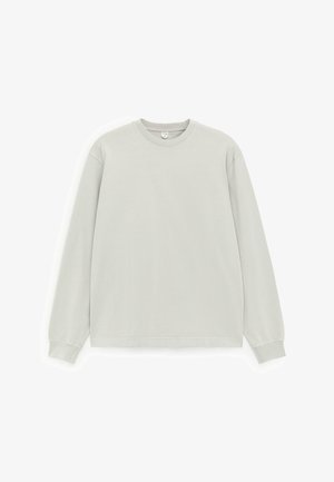 Camiseta de manga larga gris claro con cuello redondo y puños acanalados, mostrada extendida sobre un fondo blanco.