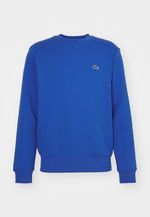 Blauwe trui met lange mouwen en ronde hals, met geribde manchetten en zoom, voorzien van een klein groen krokodillenlogo op de linkerborst.