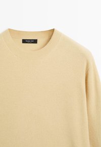 Beige knit sweater with a round neckline, ribbed collar, and textured fabric. Label reads "Massimo Dutti." Smooth texture.