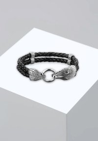 Svart flätad läderarmband med två silverfärgade djurhuvuden som lås, med detaljerade texturer och en cirkulär metallring som förbindelse.