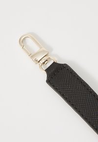Sangle en cuir noir texturé avec un clip en métal doré. Présente une finition lisse et des détails de couture précis le long des bords.