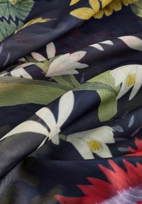 Blommönstrad tyg med en mörk marinbakgrund, som har vita och gula näckrosor, löv och röda accenter i en mjuk, texturerad väv.